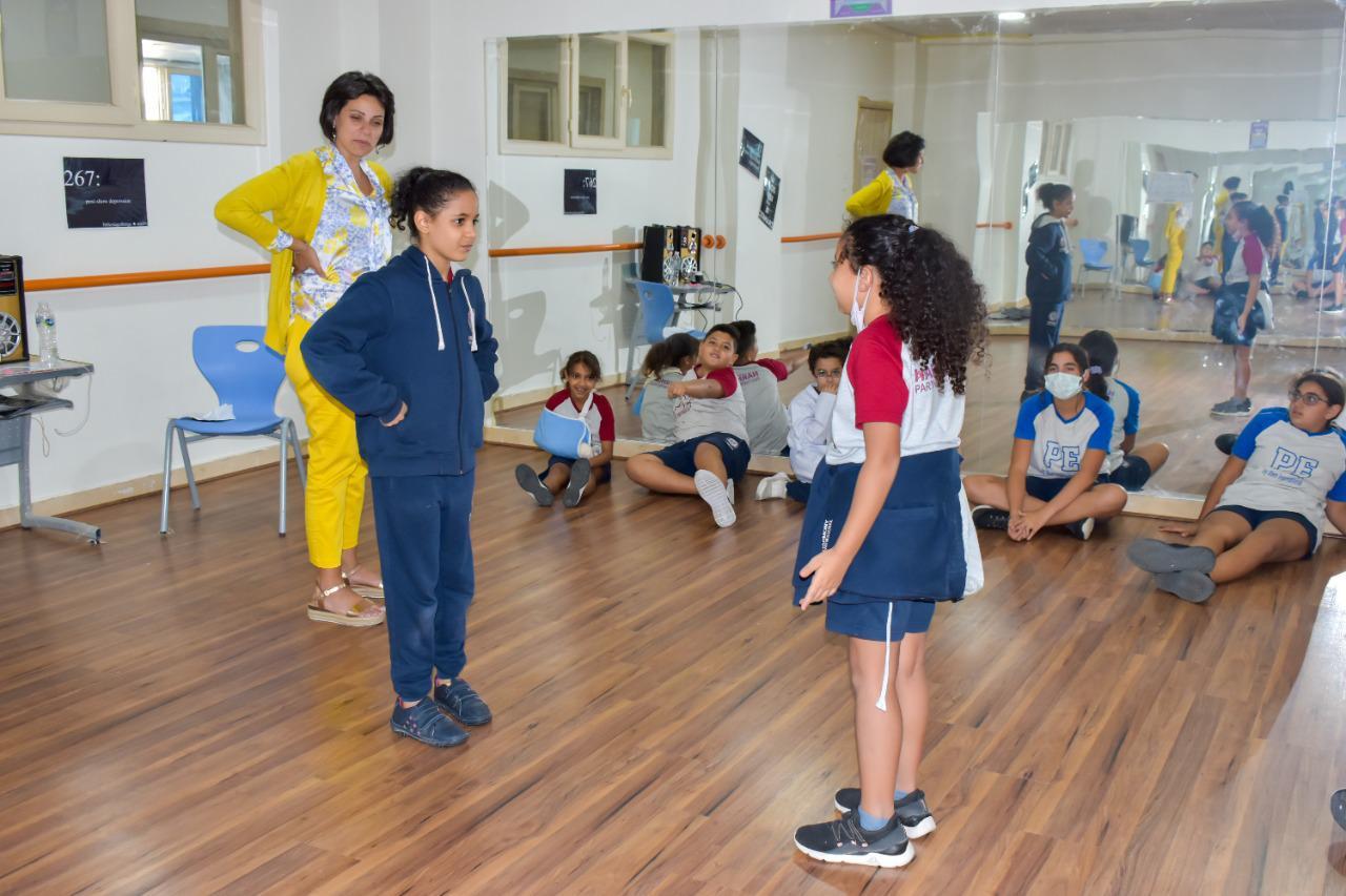 Children engaged in a dance activity in the well-lit dance studio at IVY STEM International School, with an adult teacher overseeing their performance and ensuring health and safety measures.